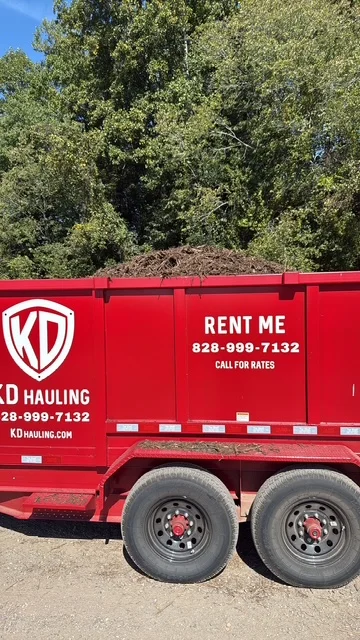 Red dual-axle hauling trailer loaded with mulch and wood debris