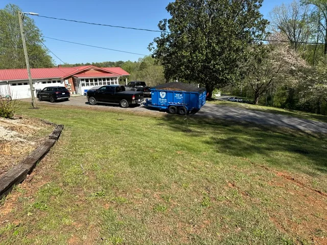 Blue dumpster trailer positioned at residential property for junk removal and hauling services