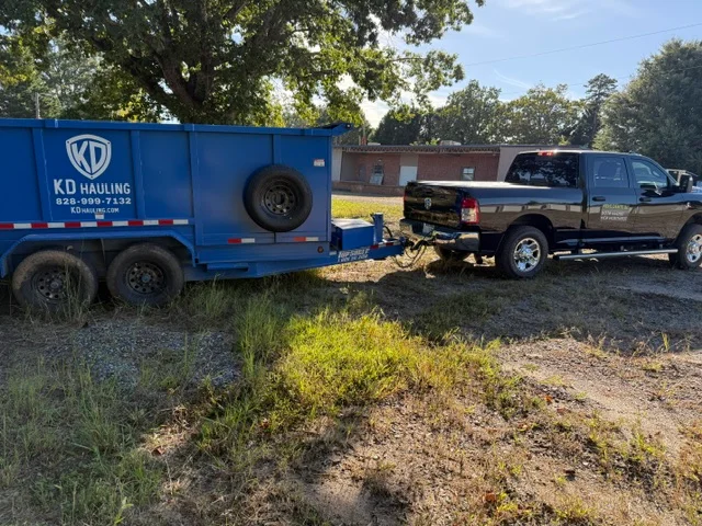 Blue dual-axle hauling trailer and brown pickup truck loaded with residential debris and junk removal materials
