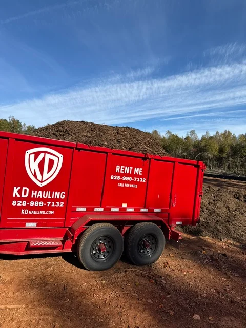 Red dump trailer loaded with soil and bulk debris material at job site