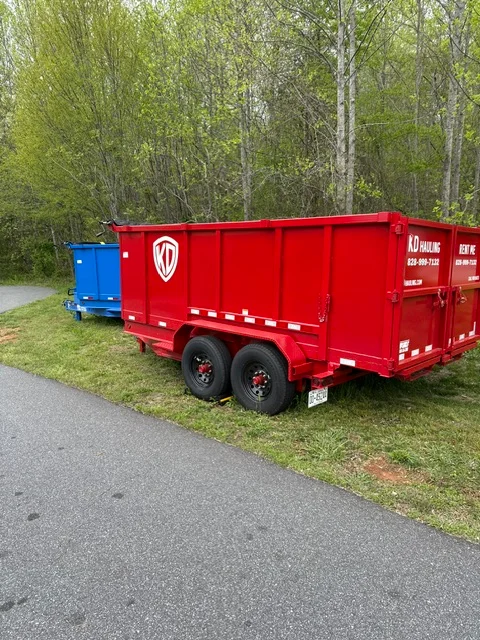 Red dual-axle dump trailer with steel construction and safety striping at residential site