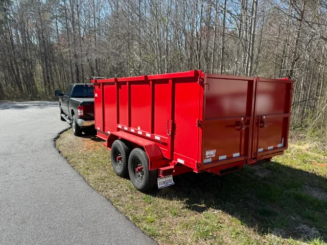 Red dual-axle dump trailer with steel construction and hydraulic gates