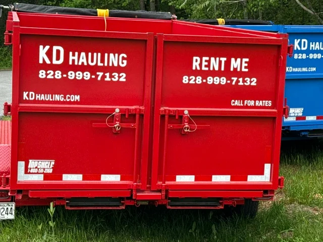 Red steel hauling trailer with dual rear doors, white vinyl lettering, and metal tie-down hardware