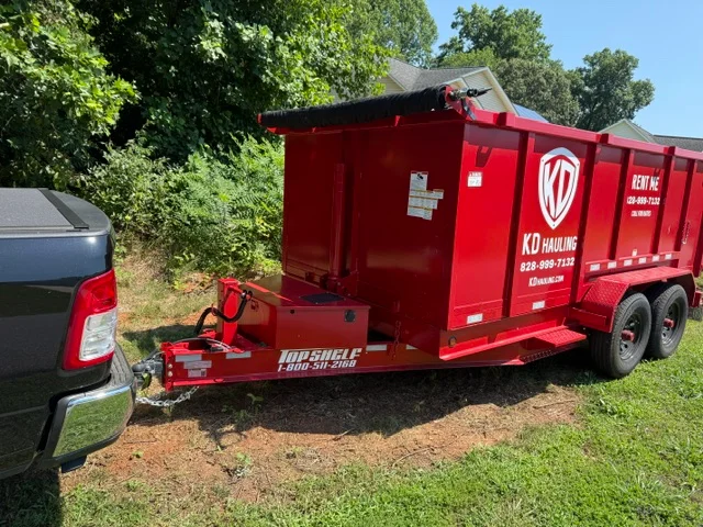 Red dual-axle dump trailer with hydraulic lift system for junk hauling