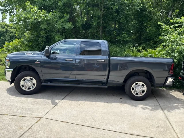 Gray crew cab pickup truck with open bed, parked on concrete driveway