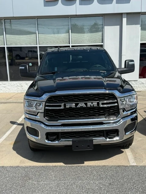 Black Ram pickup truck with polished chrome grille and trim, parked in front of commercial building