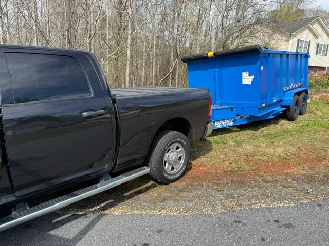Black pickup truck with blue enclosed hauling trailer on residential driveway