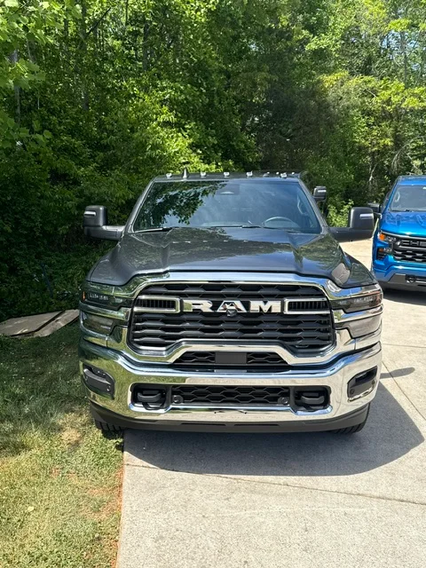 Detailed RAM pickup truck with chrome grille and polished exterior, parked alongside fleet vehicles