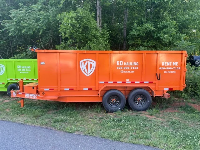 Orange dual-axle hauling trailer with custom vinyl branding and safety striping